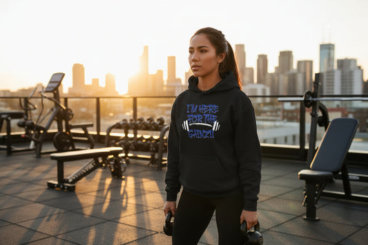 A woman wearing a black hoodie with blue text that says I'm Here For The Gainz!! with a city background.