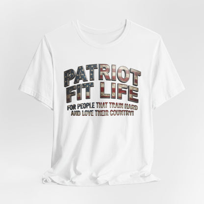 A white short-sleeve crewneck t-shirt with a graphic text print reading 'PATRIOT FIT LIFE' in a distressed American flag pattern, and 'FOR PEOPLE THAT TRAIN HARD AND LOVE THEIR COUNTRY!' underneath, shown on a light gray background.