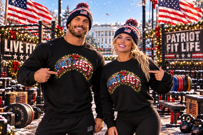 A man and a woman pose together outdoors in matching black crewneck sweatshirts with a colorful 'PATRIOT' graphic across the chest, paired with matching beanie hats featuring American flag patterns. The background is a festive, snowy outdoor gym decorated with American flags, holiday lights, and banners.