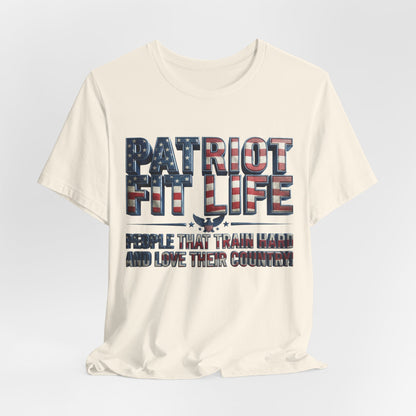 An off-white crewneck t-shirt with a patriotic graphic on the front. The graphic features the text 'PATRIOT FIT LIFE' in a distressed American flag pattern, with a white eagle silhouette in the center, and the phrase 'PEOPLE THAT TRAIN HARD AND LOVE THEIR COVENANT' printed below in a dark serif font.