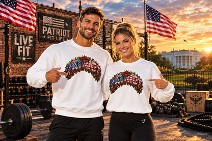 A man and a woman posing together in a gym setting at sunset, wearing matching white crewneck sweatshirts with a patriotic 'PATRIOT FIT LIFE' graphic on the chest, pointing at their designs.