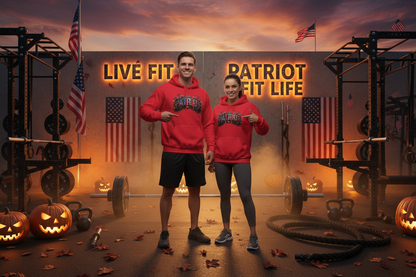A man and a woman stand in a gym wearing matching red hoodies with a Halloween PATRIOT graphic design across the chest. The background features a large sign reading 'LIVE FIT PATRIOT FIT LIFE' with American flags, weight racks, kettlebells, and jack-o'-lanterns on the floor.