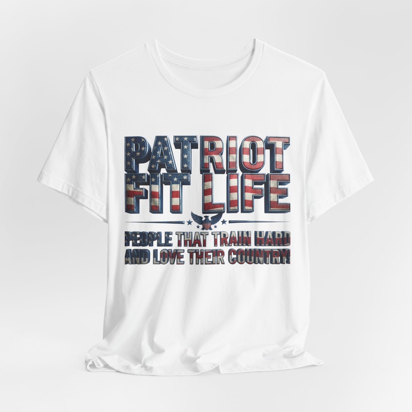 A white short-sleeve crewneck t-shirt with a patriotic graphic on the front. The graphic features the text 'PATRIOT FIT LIFE' in a distressed American flag pattern of red, white, and blue, with a small eagle silhouette in the center.