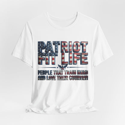 A white short-sleeve crewneck t-shirt with a patriotic graphic on the front. The graphic features the text 'PATRIOT FIT LIFE' in a distressed American flag pattern of red, white, and blue, with a small eagle silhouette in the center.