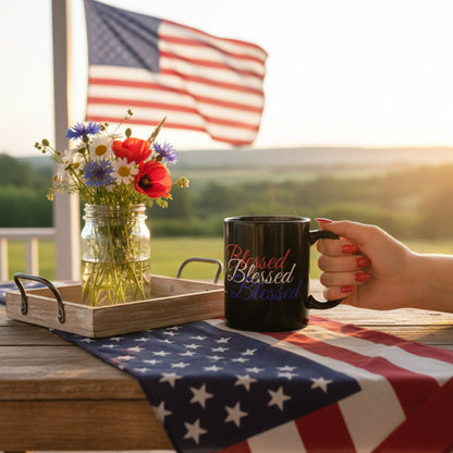 Person holding a mug with 'Blessed' text, American flag, and flowers on a table.