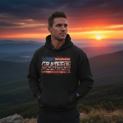 Man wearing a hoodie with 'GRATEFUL' text at sunset with mountains in the background