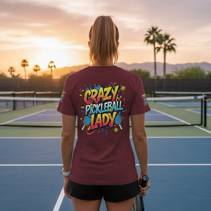 A woman wearing a 'Crazy Pickleball Lady' t-shirt on a pickleball court at sunset.
