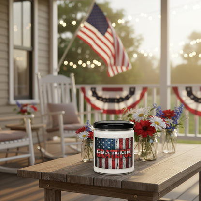 Candle jar with American flag design and 'GRATEFUL' text next to an American flag on a wooden surface.