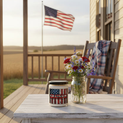 Candle jar with American flag design and 'GRATEFUL' text next to an American flag on a wooden surface.