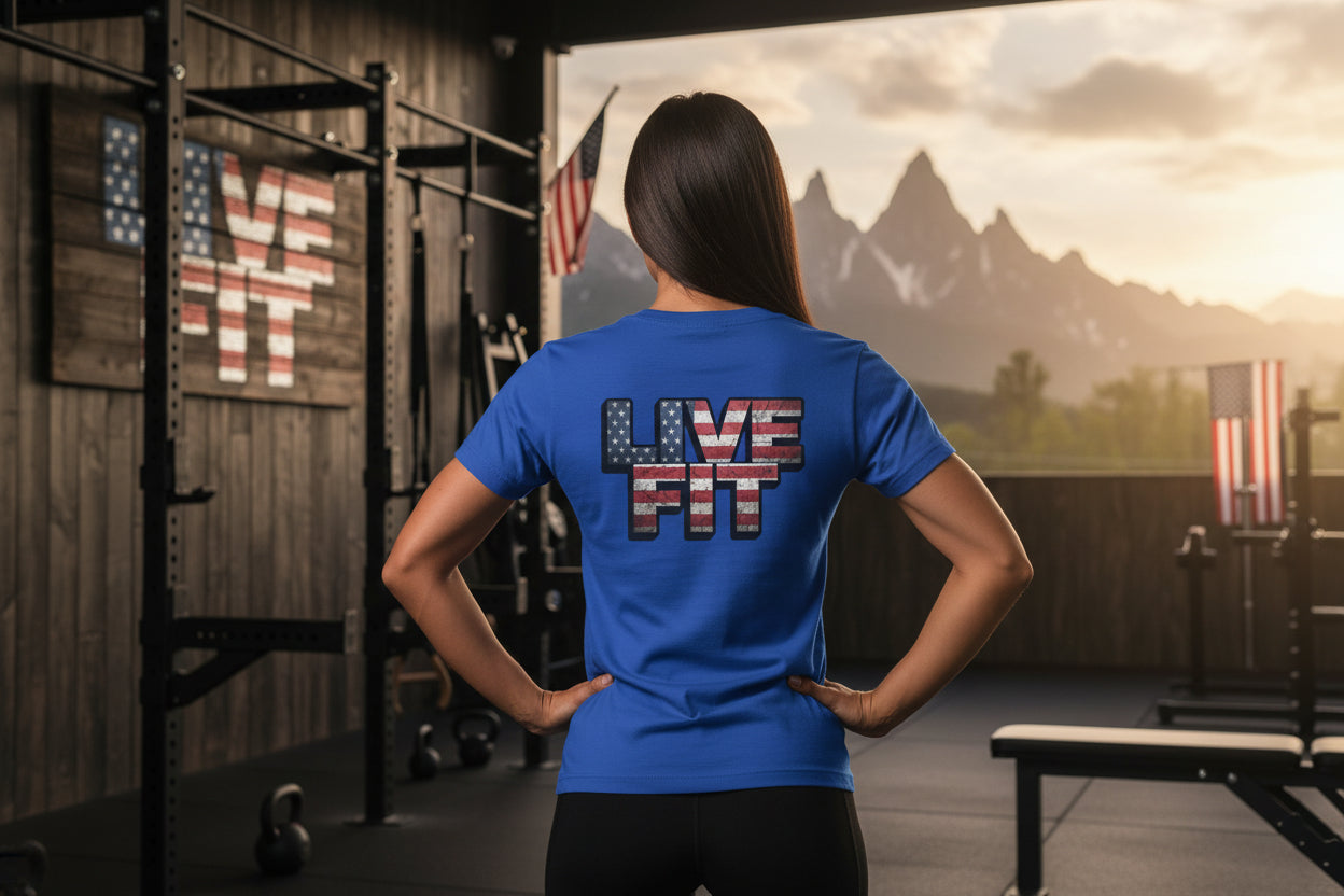 Person wearing a blue 'LIVE FIT' t-shirt in a gym setting with a scenic display on the wall.