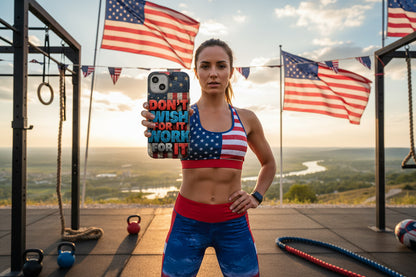 Woman in athletic wear with vintage American flag design, holding a phone with a colorful patriotic phone case that says Don’t Wish For It Work For It!, outdoors with American flags in the background.