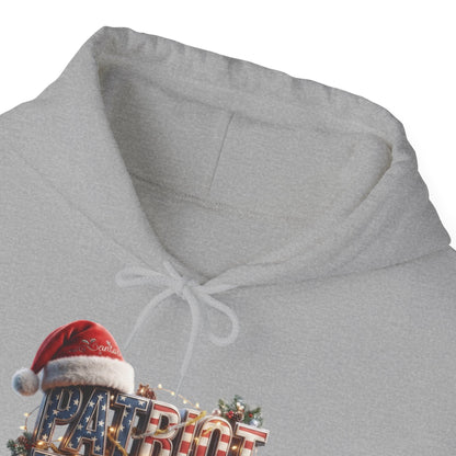 Close-up of a light gray heather hoodie with a white drawstring hood, featuring a festive Christmas 'PATRIOT' graphic with a red Santa hat on the chest.