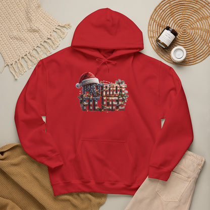 A red pullover hoodie laid flat on a light beige surface, featuring a festive chest graphic that reads 'PATRIOT FIT LIFE' with a Santa hat. 
