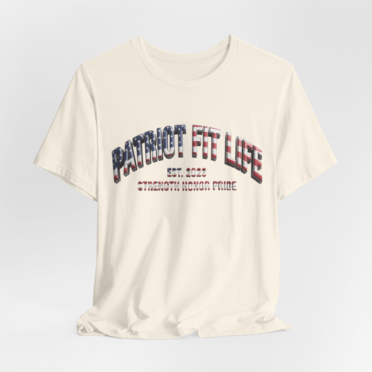 An off-white short-sleeve t-shirt with a distressed graphic on the chest reading 'PATRIOT FIT LIFE EST. 2023 STRENGTH HONOR PRIDE' in a patriotic red, white, and blue pattern, shown against a light gray gradient background.