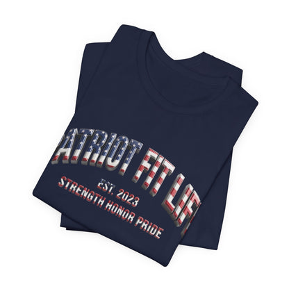 A navy blue folded t-shirt with a patriotic graphic on the front. The graphic features the text 'PATRIOT FIT LIFE' in a 3D block font filled with an American flag pattern and 'EST. 2023 STRENGTH, HONOR, PRIDE.'