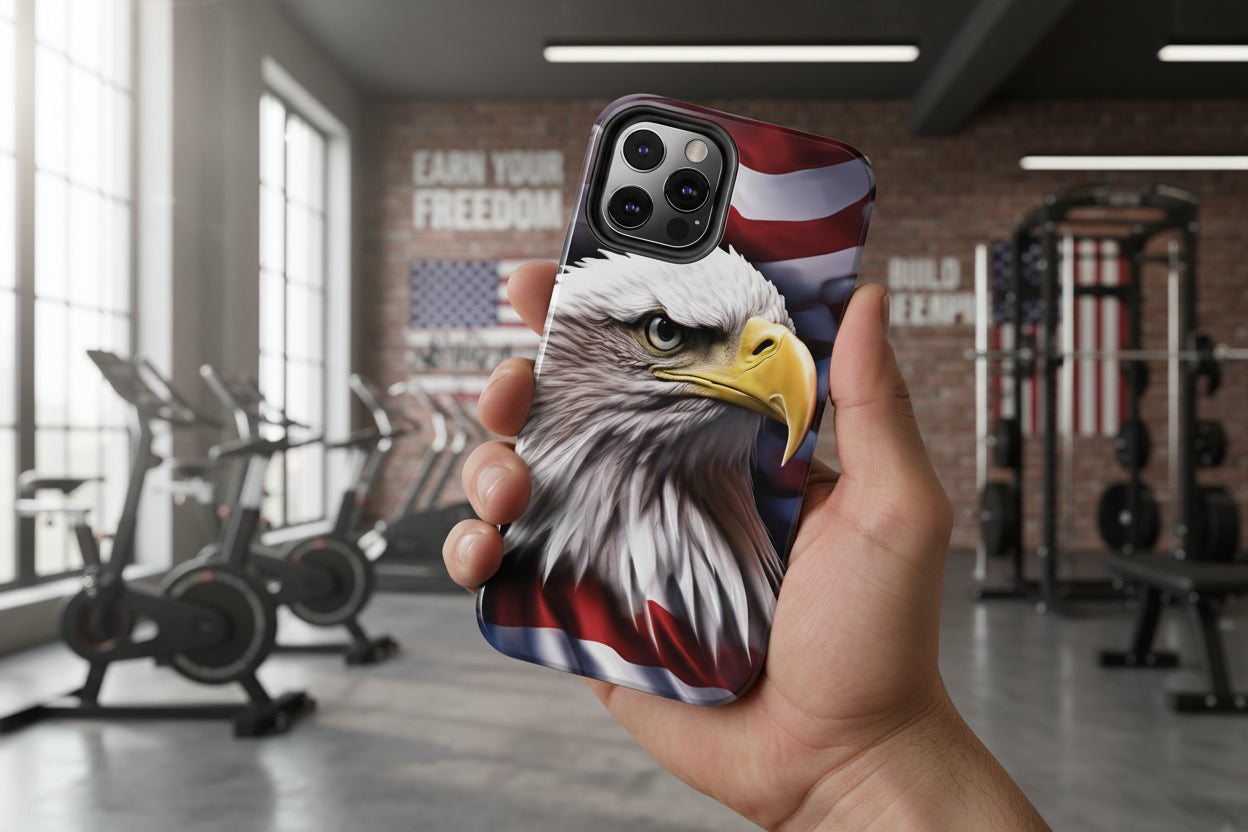 A phone case with an American flag and bald eagle design held in an indoor gym setting.