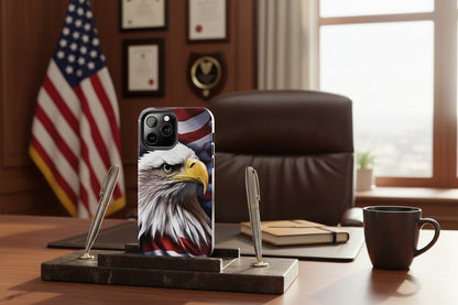 A phone case with an American flag and bald eagle design on a desk with an American flag and office chair in the background.