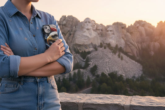 A woman holding a patriotic eagle and American flag phone case with Mount Rushmore in the background.