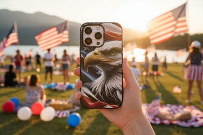 A person holding a phone with an eagle American flag design at a lakeside gathering with American flags.