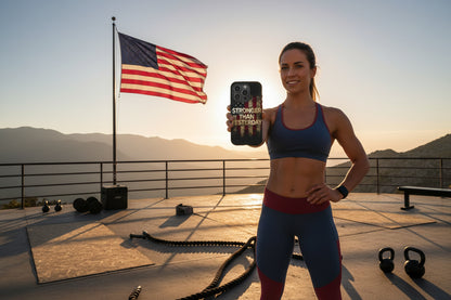 A woman showing a Stronger Than Yesterday phone case with an American flag and workout equipment in the background.