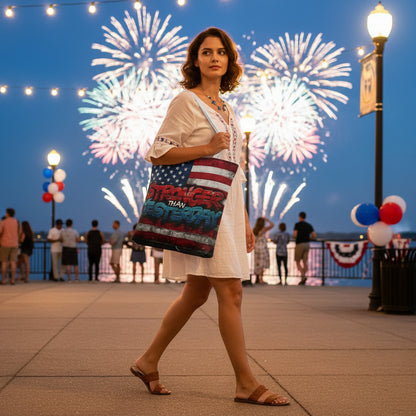 Woman holding a bag with an American flag and a "Stronger Than Yesterday design against a backdrop of fireworks.
