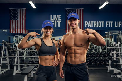 A fitness-themed promotional photo showing a smiling woman in a gray sports bra and royal blue cap posing next to a shirtless man in black shorts and a blue cap inside a gym. The background features a dark blue wall with 'LIVE FIT' and 'PATRIOT FIT LIFE' text, American flags, and gym equipment.