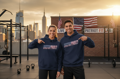 A man and a woman standing on an outdoor gym rooftop at sunset, both wearing matching navy blue hoodies with a patriotic red, white, and blue UNSTOPPABLE! text graphic on the chest. The background features a brick wall with American flags, a sign reading 'PATRIOT FIT LIFE,' and a city skyline in the distance.