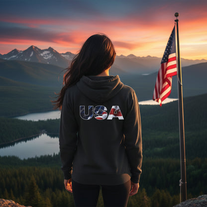 A woman wearing a hoodie with 'USA' on the back, standing in front of a scenic landscape with mountains and an American flag.