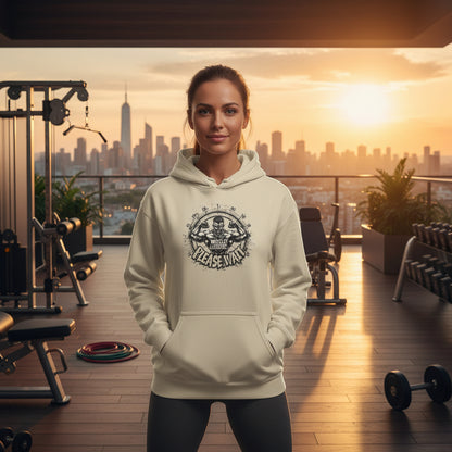 A woman is wearing a beige hoodie with a graphic design that says Muscles Loading Please Wait in a scenic outdoor gym setting.