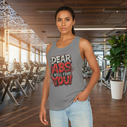 Woman wearing a tank top with a humorous fitness-themed design that says Dear Abs I Will Find You! in a gym setting.