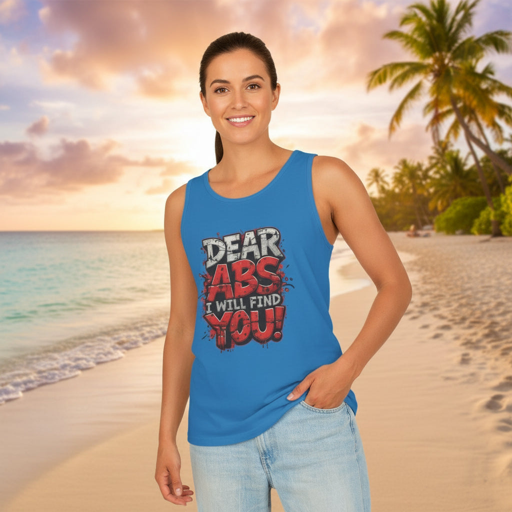 Woman wearing a blue tank top with text that says Dear Abs I Will Find You! on a beach at sunset