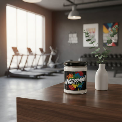 Candle labeled 'Unstoppable!' on a table with a blurred gym background