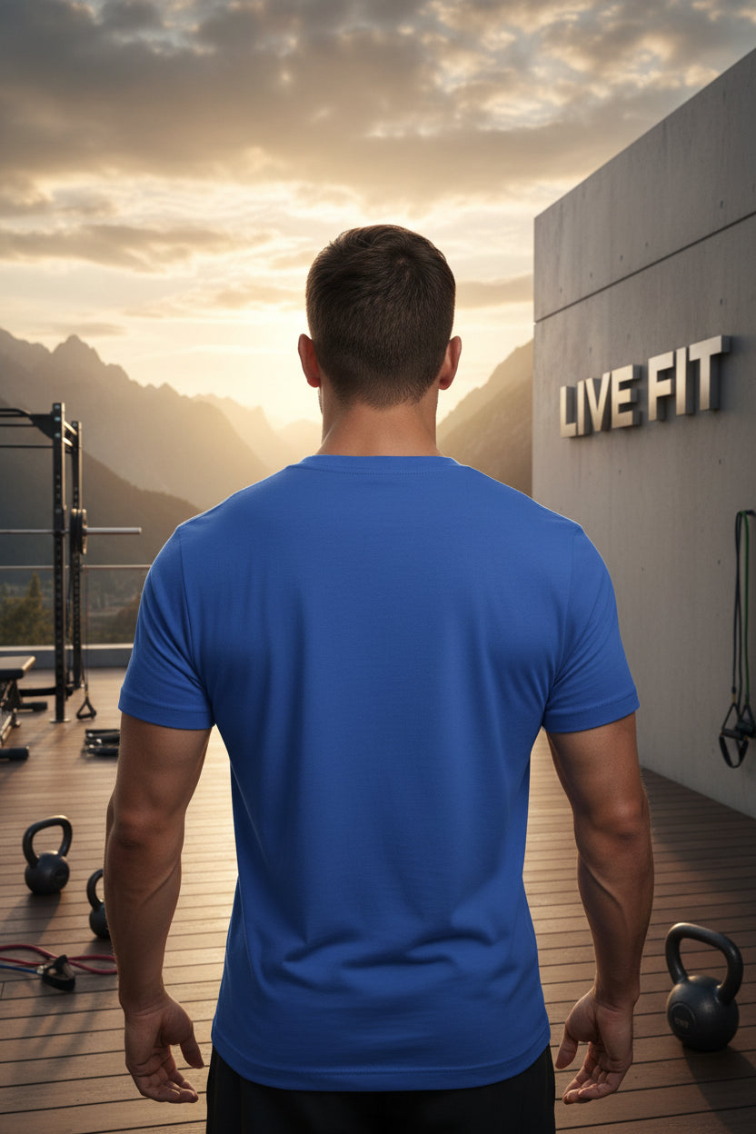 Man in a blue t-shirt standing on a rooftop with 'Live Fit' branding and sunset view.