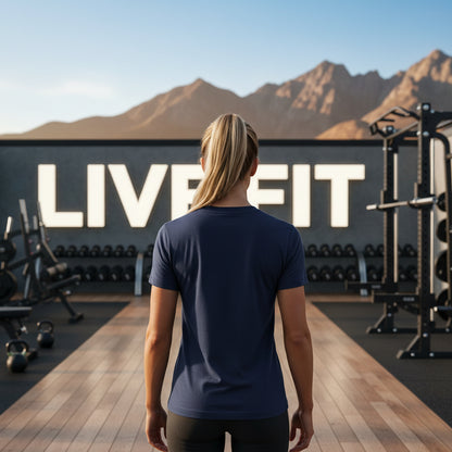 Person standing in a gym with mountains in the background, wearing a blue shirt.